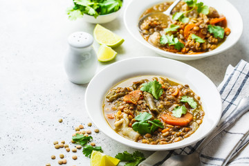 Lentil soup with vegetables in a white plate, white background. Plant based food, clean eating.