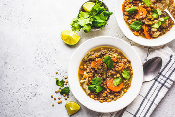 Lentil soup with vegetables in a white plate, white background. Plant based food, clean eating.