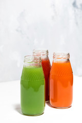 colorful vegetable juices in bottles on white background, vertical