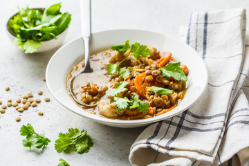 Lentil soup with vegetables in a white plate, white background. Plant based food, clean eating.
