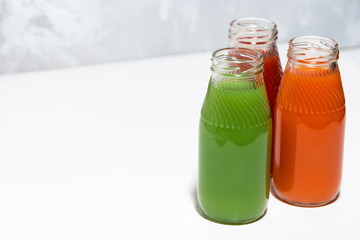 colorful vegetable juices in bottles on white table, top view