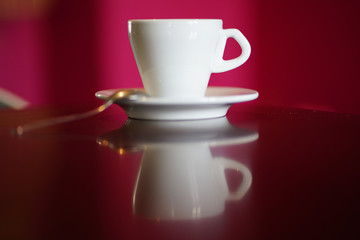 isolated white coffee cup with plate and spoon with reflection and red background