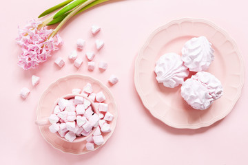 Fototapeta na wymiar Pink marshmallow and pink merengue in pink dishes and pink hyacinth on pink background