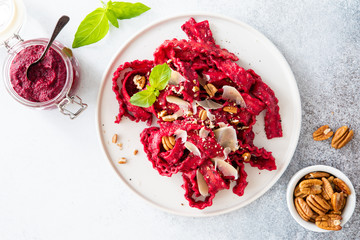 Top view of vegetarian mafaldine pasta with beet pesto sauce, walnut and parmesan cheese on a white background