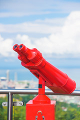 Red binoculars on the observation deck in Batumi. Large binoculars on a stand against the cloudy...