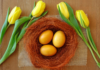  Jajka barwione kurkumą otoczone żółtymi tulipanami i brązowym sizalem