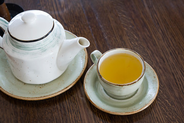 Tea ceremony. On the brown wooden surface there is a ceramic teapot and a mug of sea buckthorn tea.