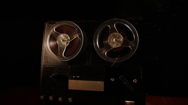 Old vintage reel to reel player and recorder on dark toned foggy background. Analog Stereo Open Reel Tape Deck Recorder Player with Reels. Selective focus