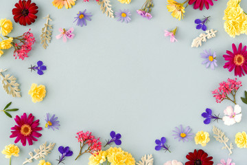 Colored  floral pattern with spring flowers and leaves with copy space on blue background. Flat lay. Top view