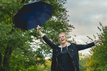 A young woman holds up her umbrella and cheers