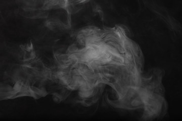 White smoke on a black background. Texture of smoke. Clubs of white smoke on a dark background for an overlay