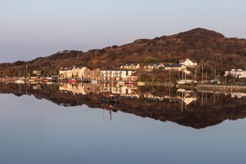 Pier and buildings reflected in Clifden bay