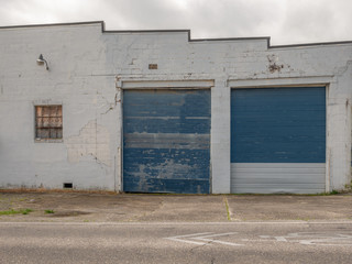 Fototapeta na wymiar old block industrial building with window and blue overhead doors
