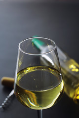 Transparent bottle of white dry wine on the table. White wine glass on a wooden background.