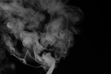 White smoke on a black background. Texture of smoke. Clubs of white smoke on a dark background for an overlay