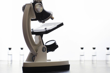 Research laboratory. Test tubes and microscope on the table on a white background.