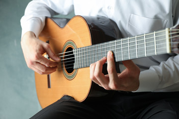 Fototapeta na wymiar Man playing on classic guitar against light background, space for text