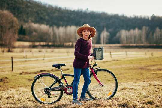 Cute little ten year old girl riding bicycle on countryside.