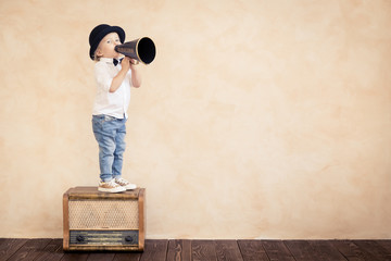 Funny child playing with black retro megaphone