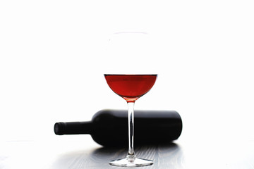 A glass of red dry wine on the table. Dark bottle and glass of wine.