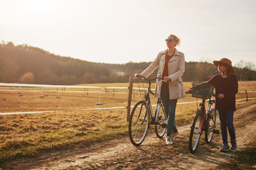 Obraz premium Mother and daughter with bicycles on countryside.