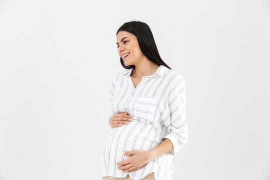 Image of caucasian pregnant woman 30s smiling and touching her big tummy