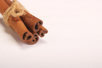 Ground cinnamon, cinnamon sticks, tied with jute hempen rope on wooden white background, selective soft focus