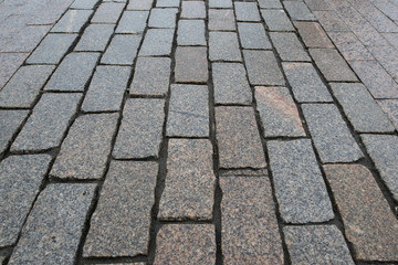 Perspective view on stone road close up. Pavement of granite. Brown square cobblestone sidewalk. Mock up or vintage grunge texture.