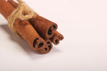 Ground cinnamon, cinnamon sticks, tied with jute hempen rope on wooden white background, selective soft focus