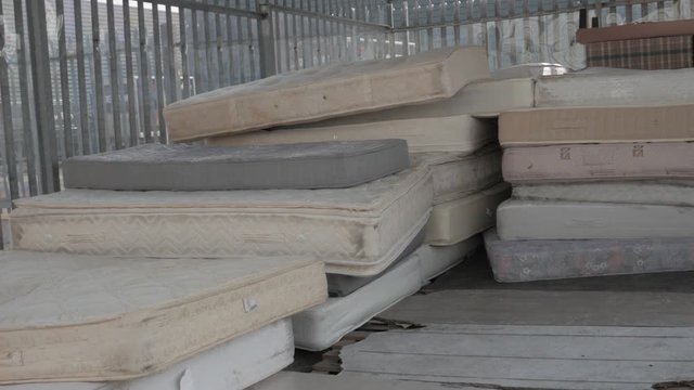 Pan left shot pile of used mattresses stocked in a warehouse, second hand concept