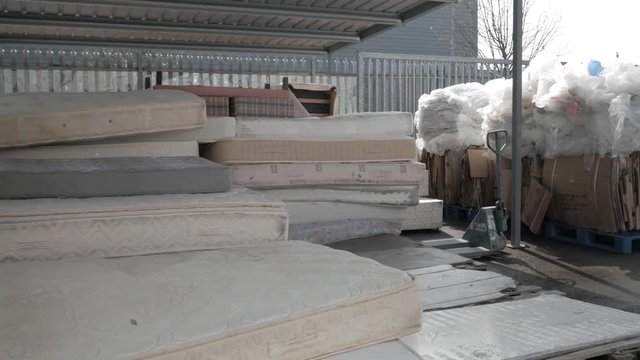 Pan right shot in a warehouse, collecting waste, selective garbage of paper, plastic and mattresses