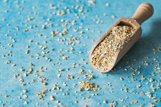 oat bran in wooden spoon, blue background