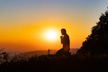Silhouette of woman praying with cross in nature sunrise background, Crucifix, Symbol of Faith....