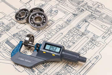 Micrometer screw gauge. Ball bearings. Drawing on background. Accurate measuring tool. Digital display. Round metal parts group. Engineering draft, plan, design. Education, study. Full depth of field.