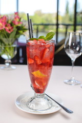 cocktail with strawberries, mint and ice in a glass tumbler