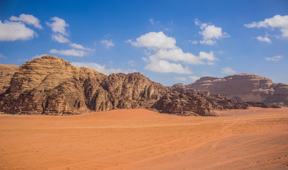 Fototapeta na wymiar Wadi Rum Jordan Middle East panorama scenery desert landscape sand valley foreground and bare rocky mountain ridge background with vivid blue sky, travel planet and discovery concept photography