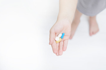 Unrecognizable child holds pills on the palm. View from above