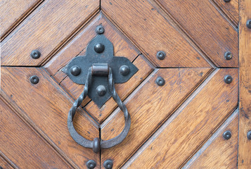 Forged metal door handle with a ring on a wooden door