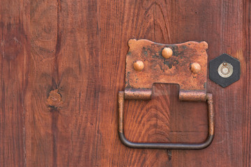 Forged metal door handle with a ring on a wooden door