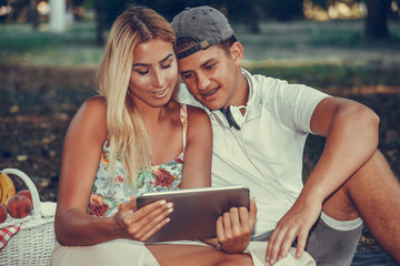 Shot of a happy young couple looking at a tablet while having a picnic