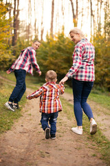 Fototapeta premium Little cute son playing with parents in forest