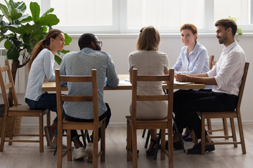 Diverse office business team talking sitting at table in boardroom