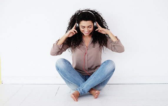 woman sitting at home and listening to music with headphones