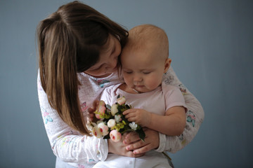 Kid girl hugging baby and holding together flowers