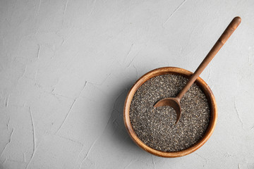 Bowl and spoon with chia seeds on grey background, top view. Space for text