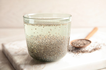 Glass of water with chia seeds and spoon on board