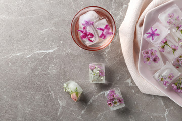 Flat lay composition with floral ice cubes on table. Space for text