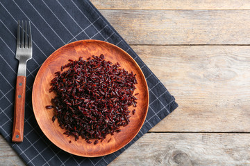 Boiled brown rice served on wooden table, top view. Space for text