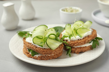 Plate with traditional English cucumber sandwiches on table