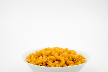Uncooked macaroni in a bowl isolated on white background with space for text, flat lay concept. 